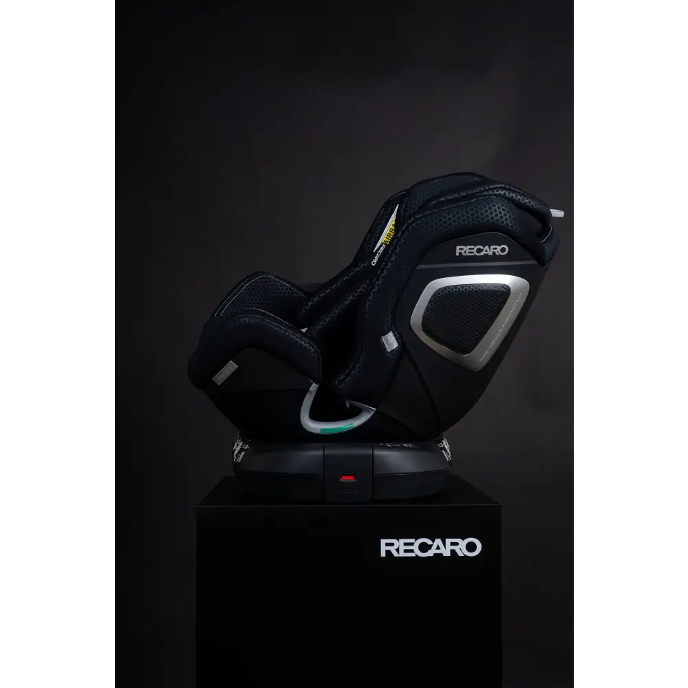 Recaro XENON 1 in Fresh Black, reclined side view on a black Recaro display pedestal.