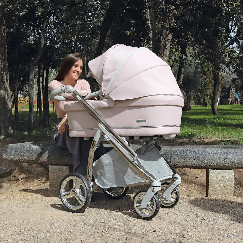 A sleek, blush-pink pram with a quilted fabric canopy and chrome-finished frame.