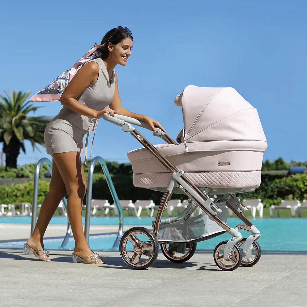 A sleek, blush-pink pram with quilted detailing and rose gold accents.