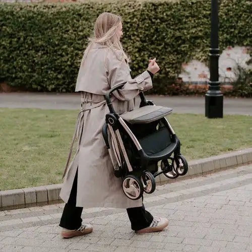 A sleek, foldable stroller with a black frame and beige fabric seat.