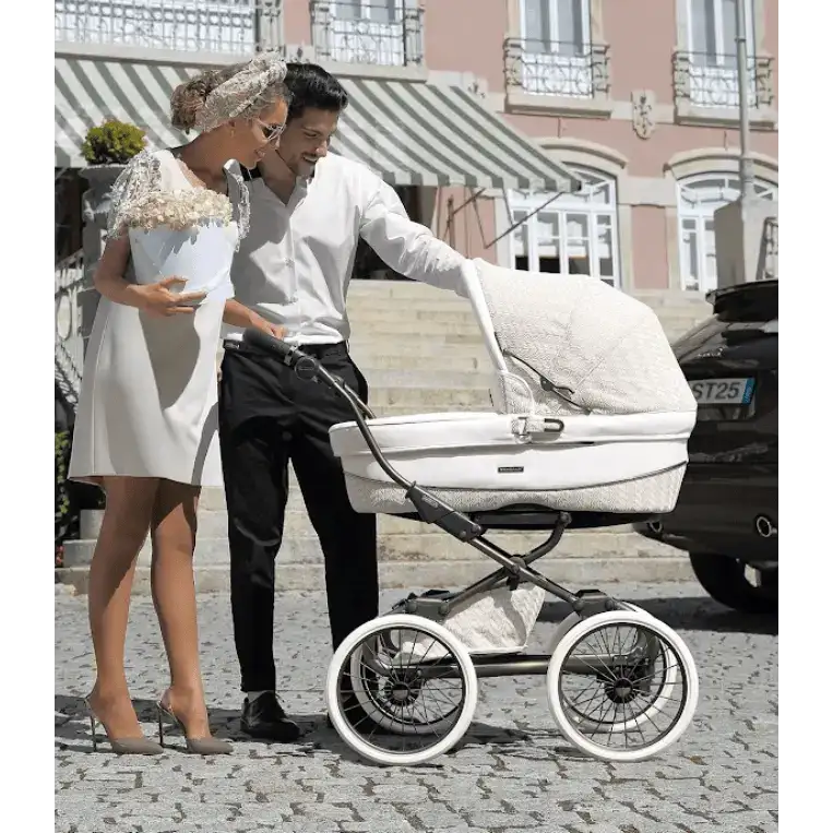 White quilted fabric pram with black metal frame and white-walled wheels
